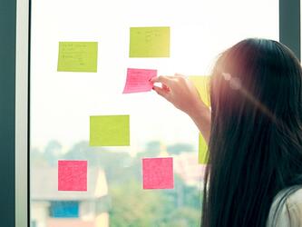 researcher looks at colourful post-it notes on window